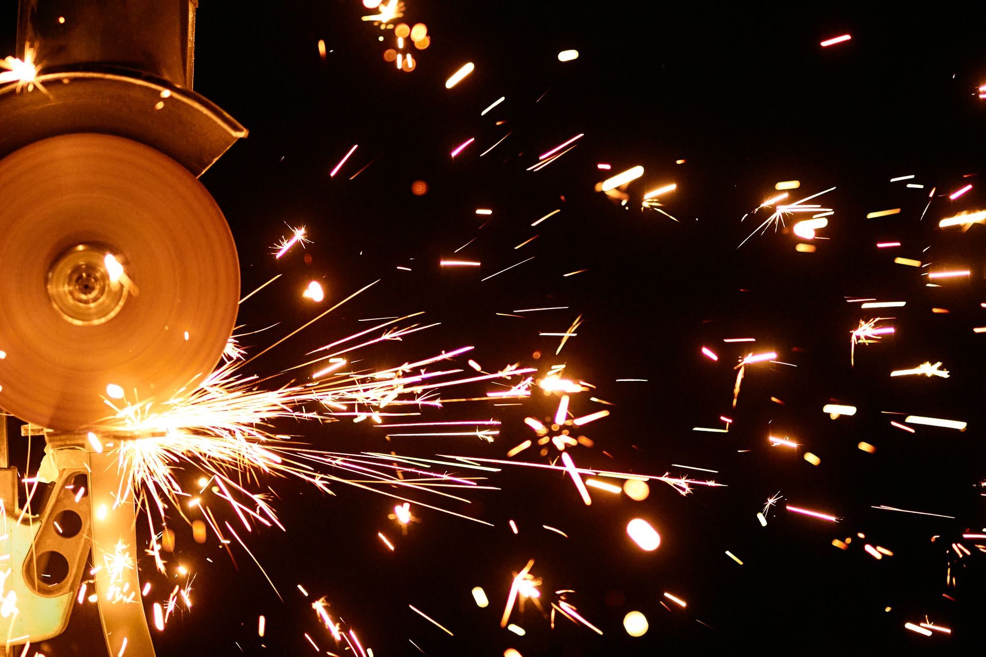 Sparks flying from an angle grinder in a dark workshop